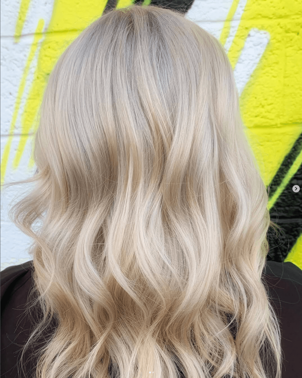 Creamy platinum blonde with soft waves and seamless root melt