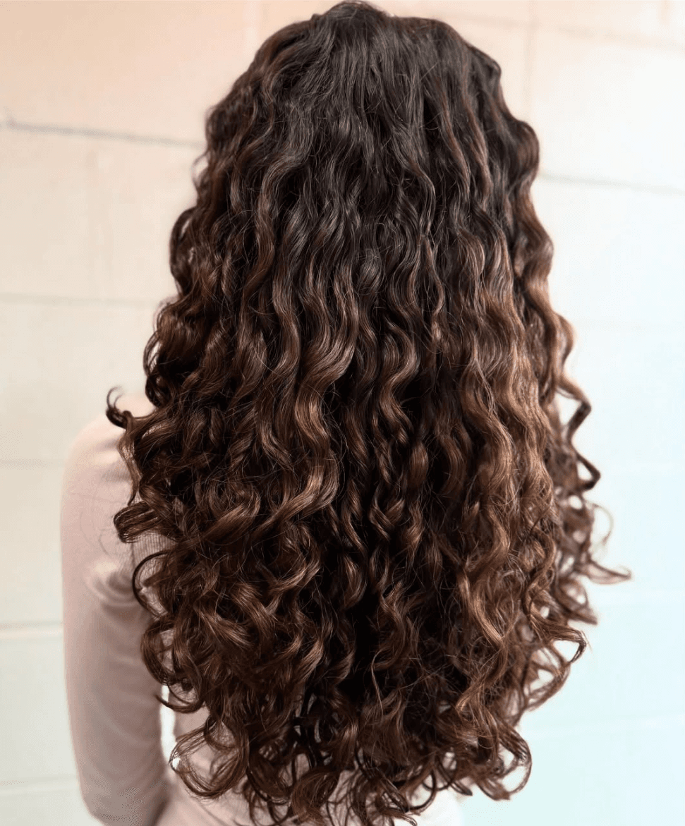 Natural brunette curls with warm caramel highlights throughout