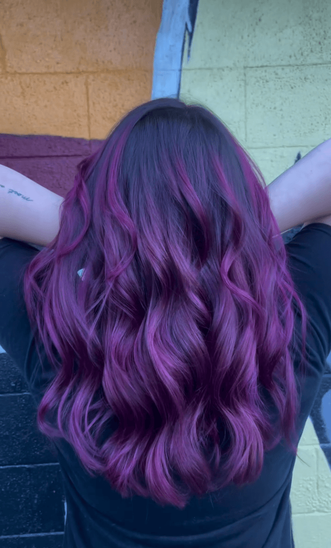 Deep purple and magenta balayage blending through dark roots into rich violet waves