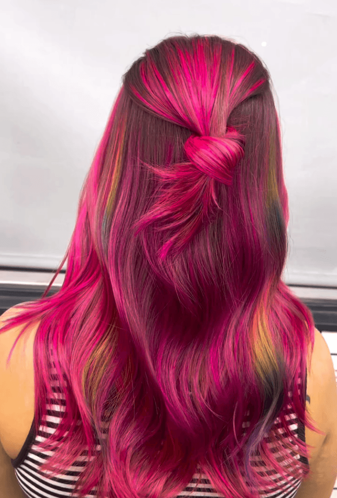 Hot pink vivid color with rainbow peekaboo strands in a half-up twisted style
